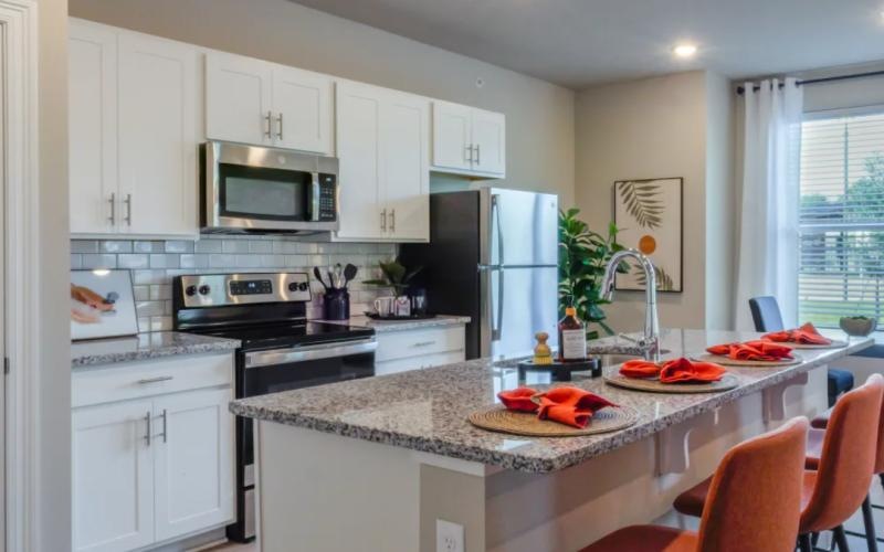 a kitchen with white cabinets and an island bar with seating