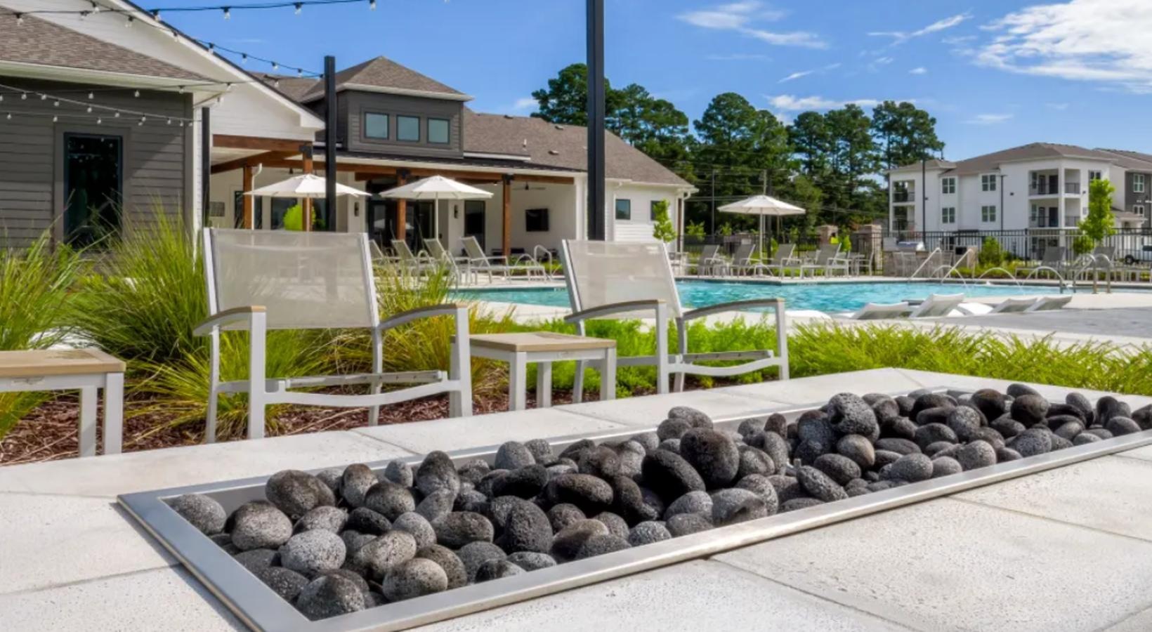 Find your perfect fit at The Flats at East Bay a pool with a table and chairs and a firepit