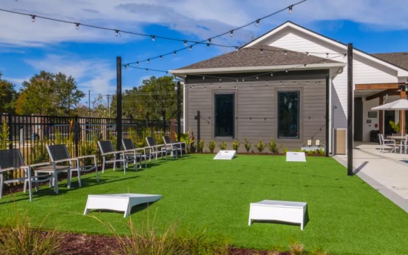 a backyard with tables and chairs and cornhole