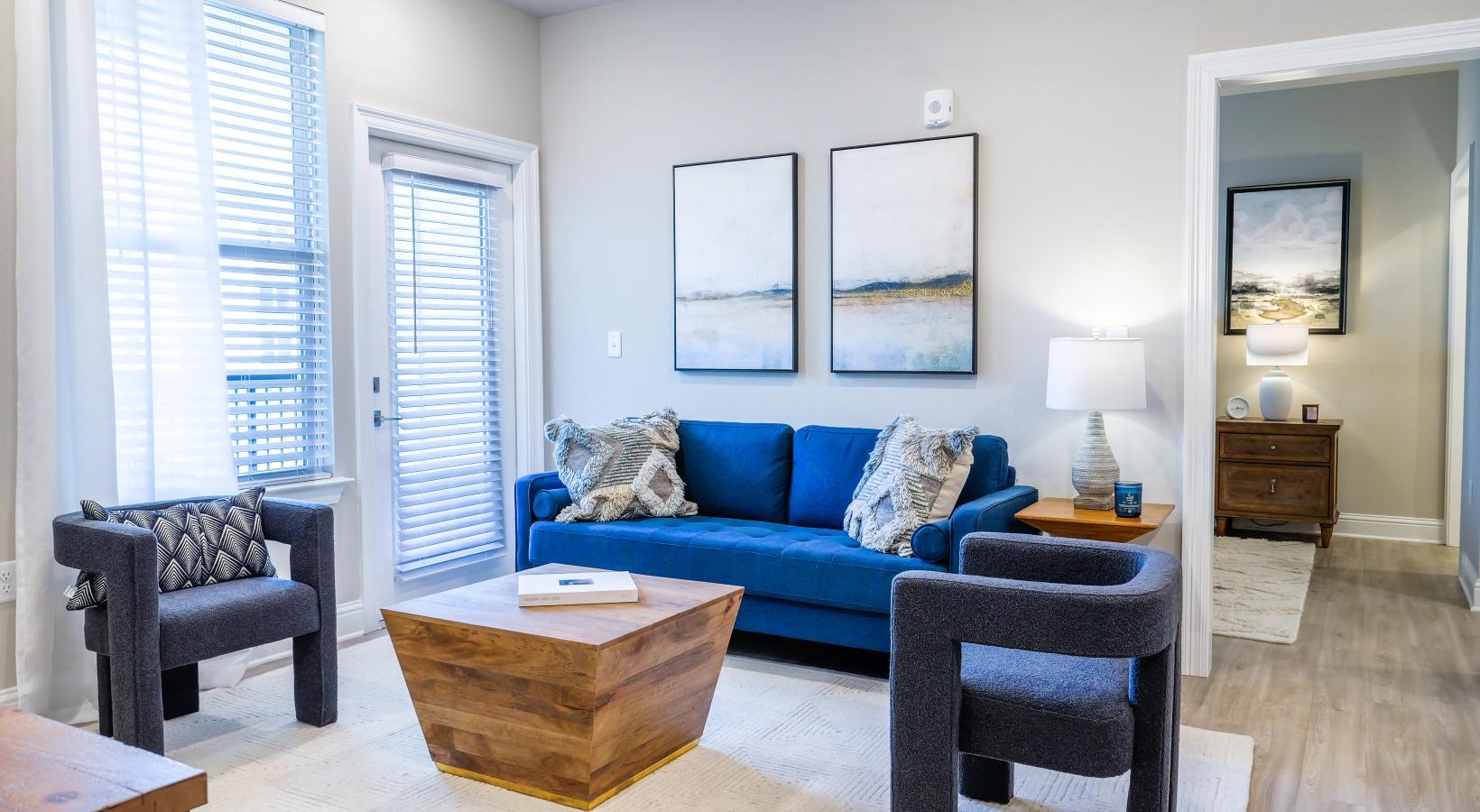 Beautiful living areas to match your lifestyle a living room with a blue couch a coffee tables chairs and a large window