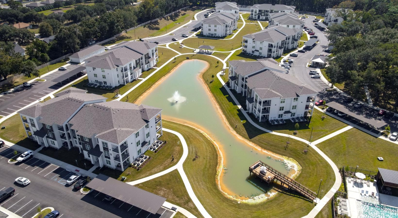 Find your perfect fit at The Flats at East Bay aerial view of a large building and a pond and a pool