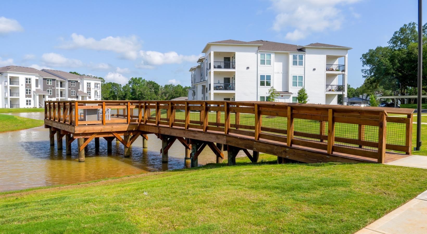 Settle into comfort at The Flats at East Bay a wooden dock over a body of water with buildings in the background